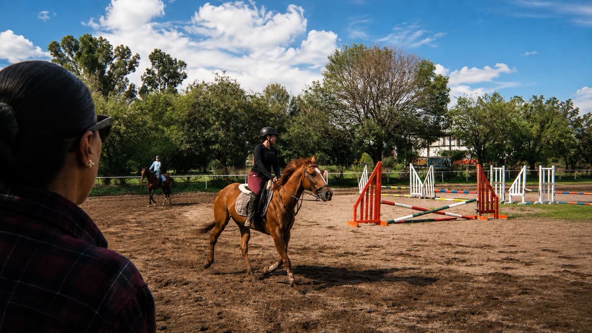 Instructora observando a una alumna entrenar sobre un caballo alazán