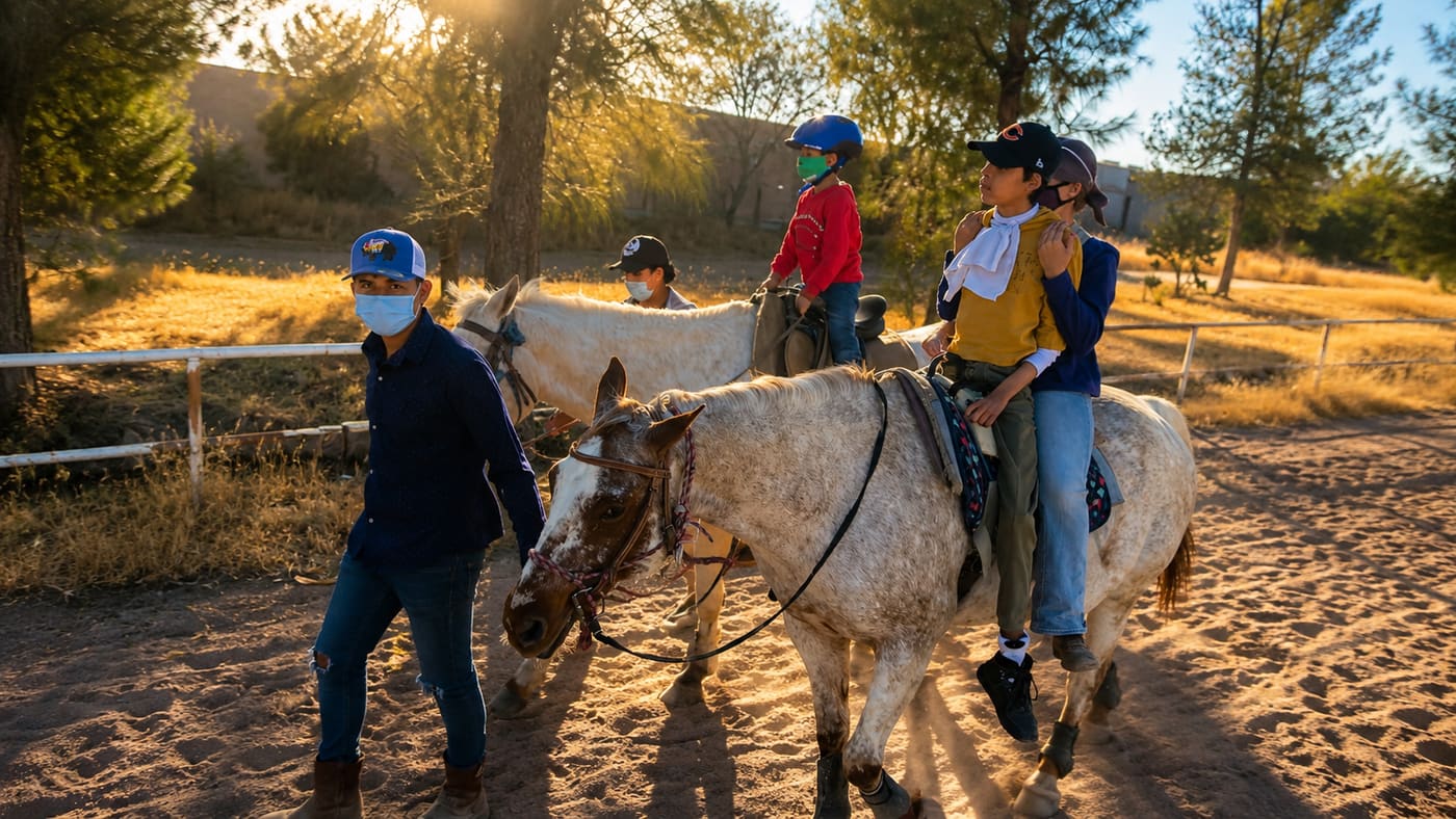 Sesión de actividades asistidas con caballos: niños y acompañantes en la arena al atardecer